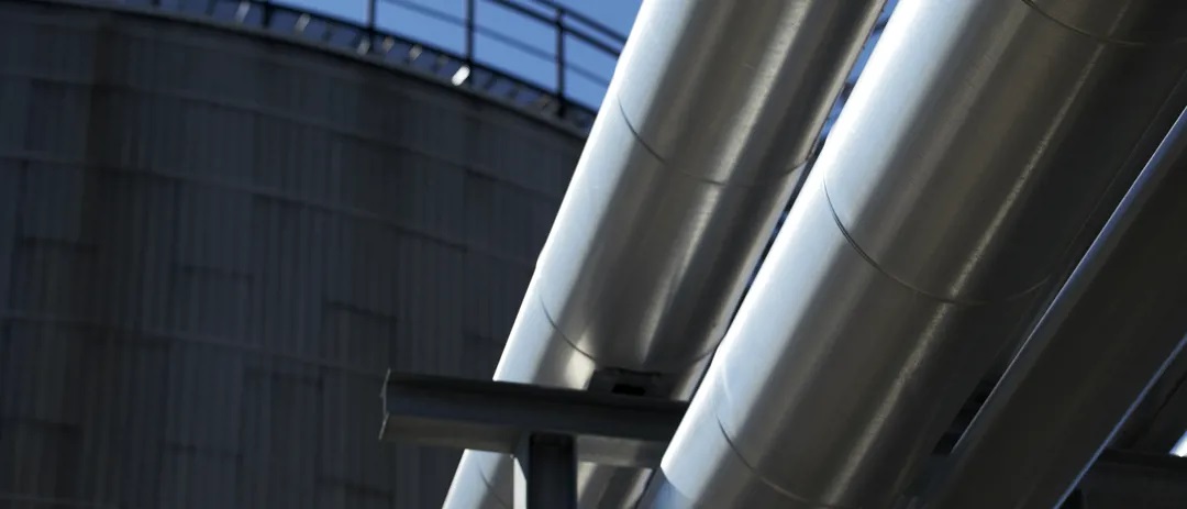 Man on top of an oil bunker in yellow clothes and a contruction helmet